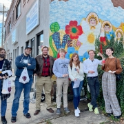 A group posing in front of a mural