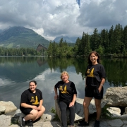 Three people standing in front of a lake