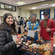 Students wearing traditional Russian garb serving food at a table