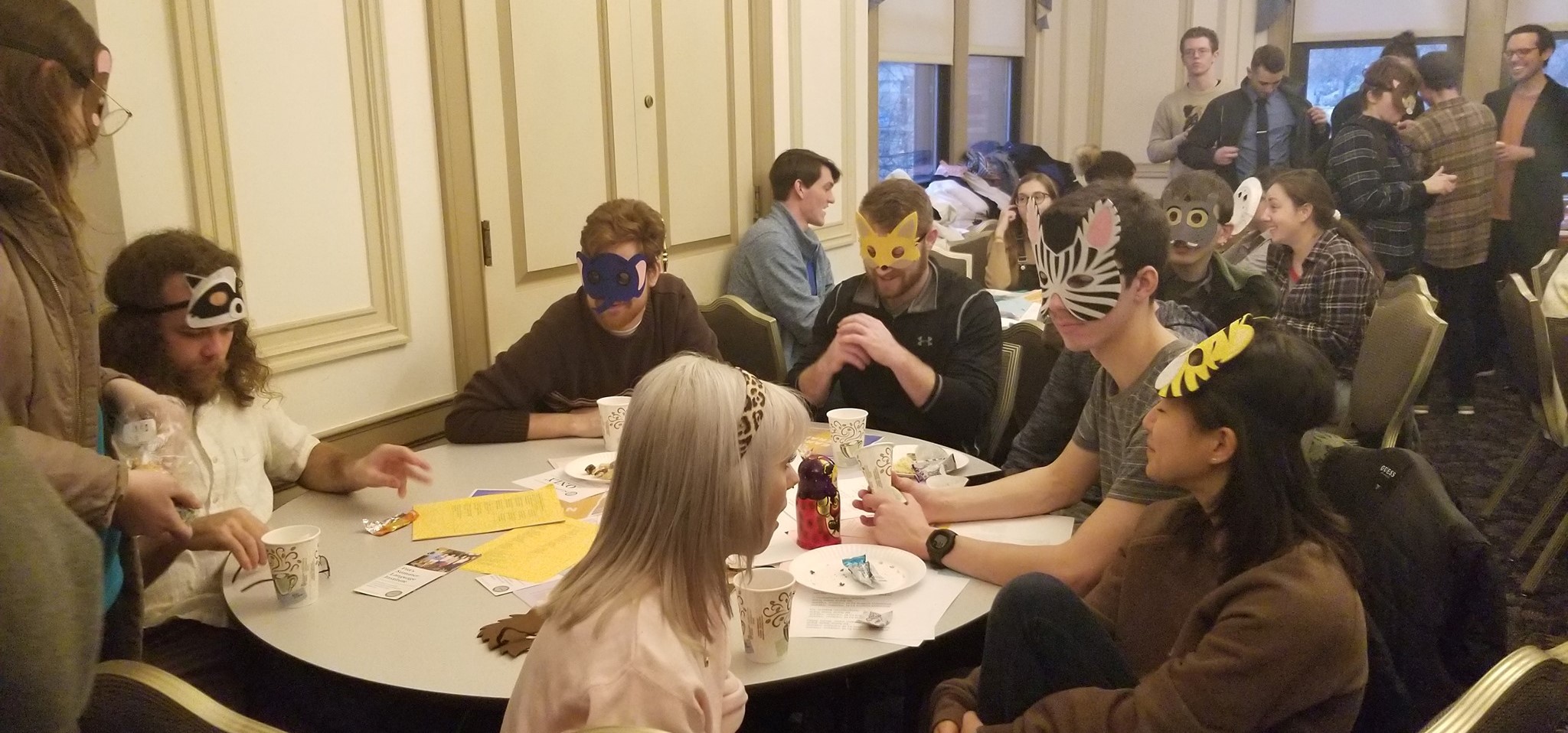 People sitting around a table in costume masks