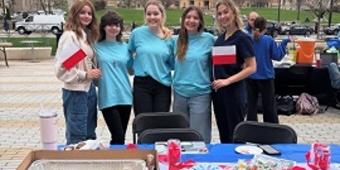 Students posing behind a table with Polish flags